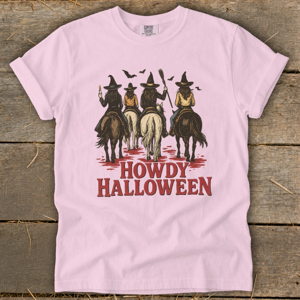Pink t-shirt with graphic of four witches on horseback and "Howdy Halloween" text.
