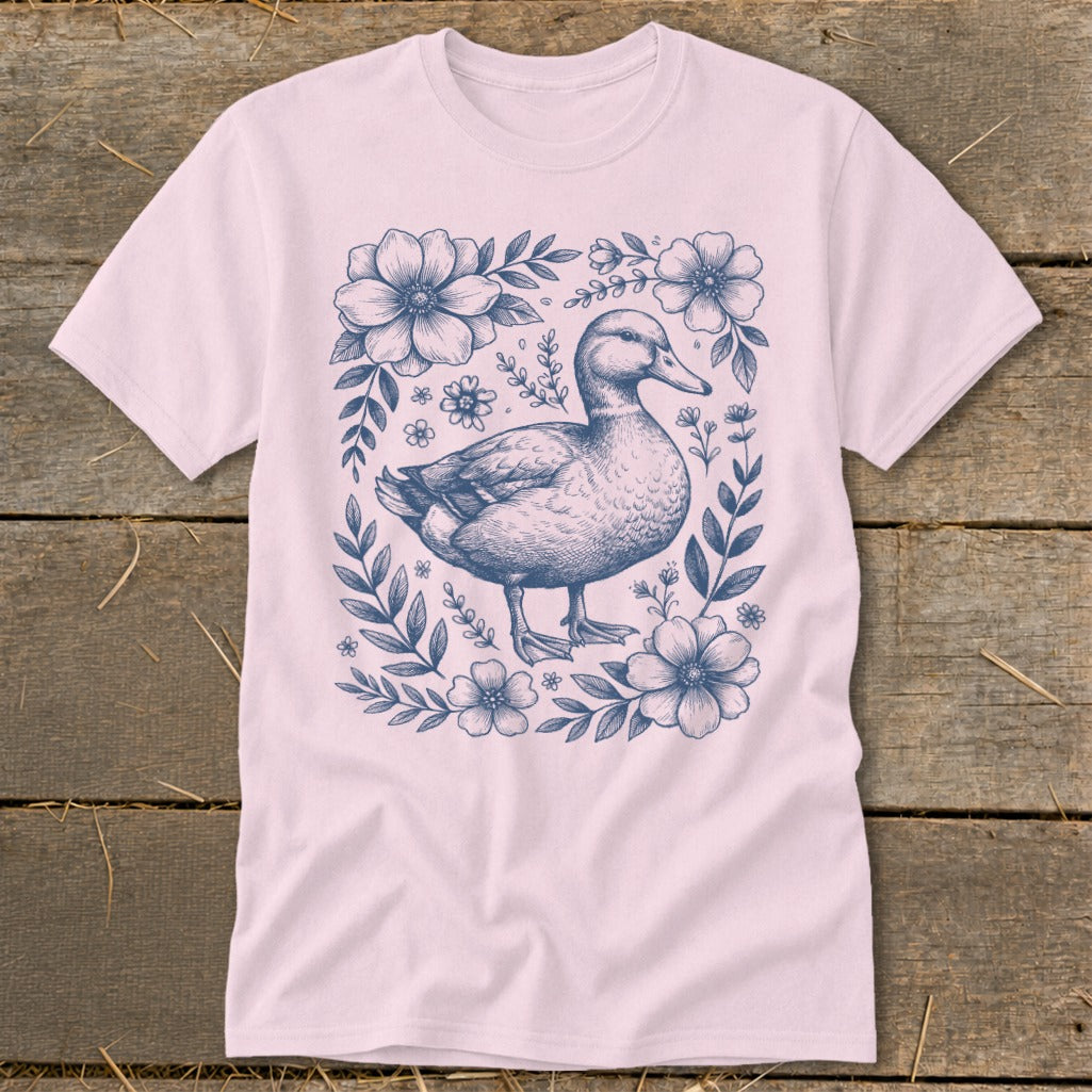 Pink t-shirt with a blue line drawing of a duck surrounded by flowers and leaves.