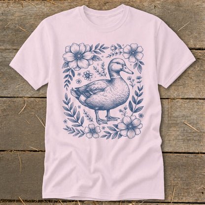Pink t-shirt with a blue line drawing of a duck surrounded by flowers and leaves.