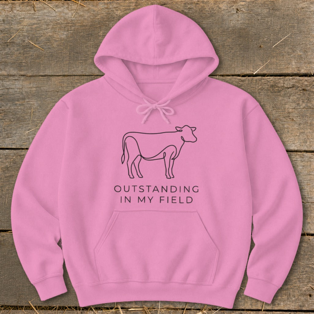 Pink hoodie with a line art cow and text "OUTSTANDING IN MY FIELD".