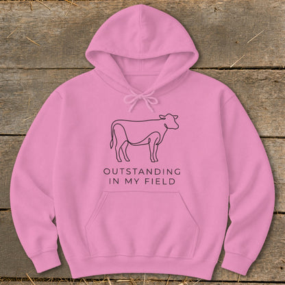 Pink hoodie with a line art cow and text "OUTSTANDING IN MY FIELD".