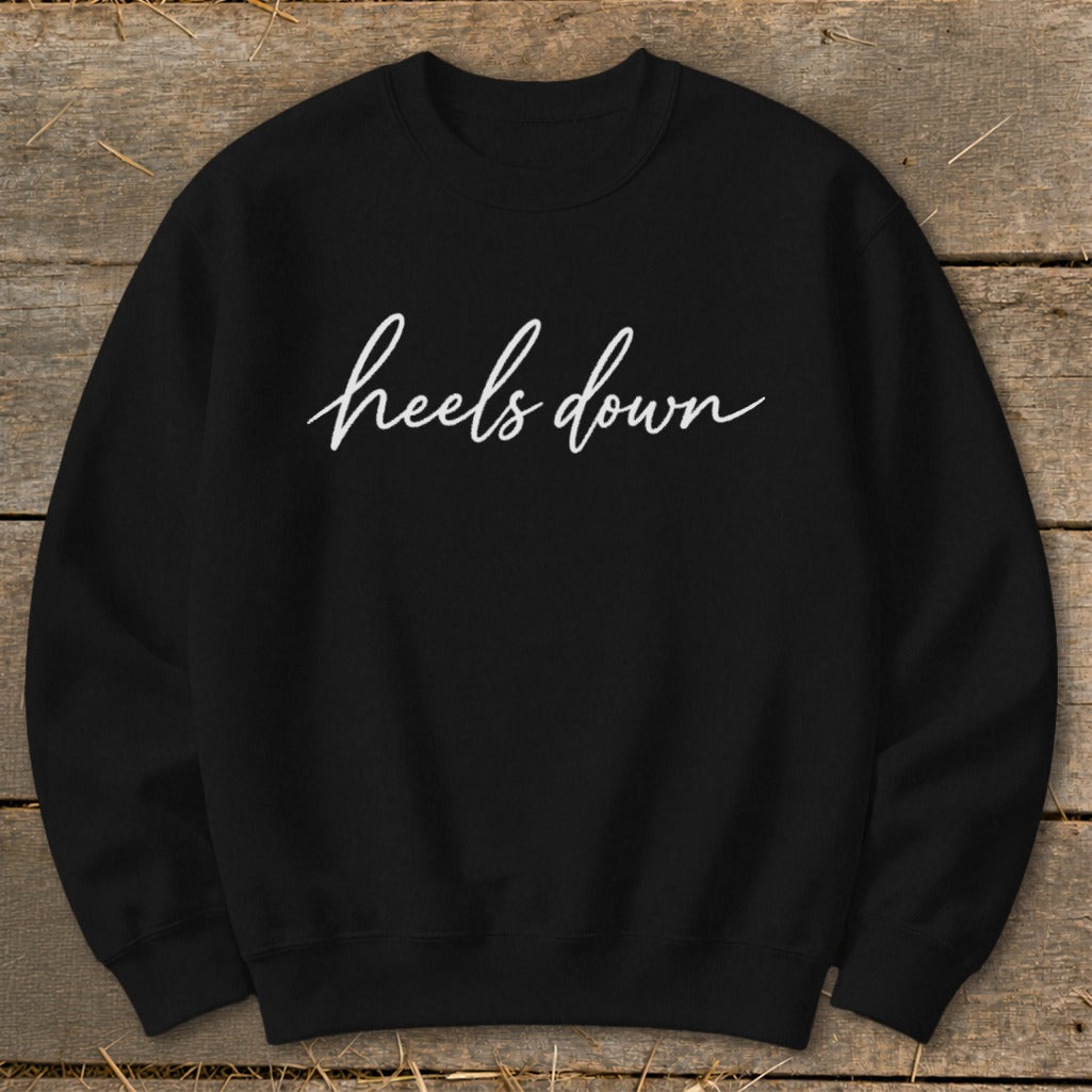Black sweatshirt with white cursive text reading "heels down".