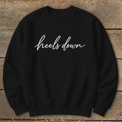 Black sweatshirt with white cursive text reading "heels down".