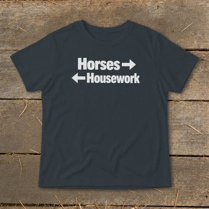 A dark grey t-shirt with white text reading Horses with a right arrow and Housework with a left arrow.