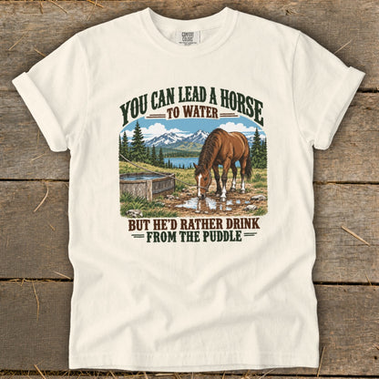 Cream-colored t-shirt with a vintage graphic of a horse drinking from a puddle and mountain scenery.