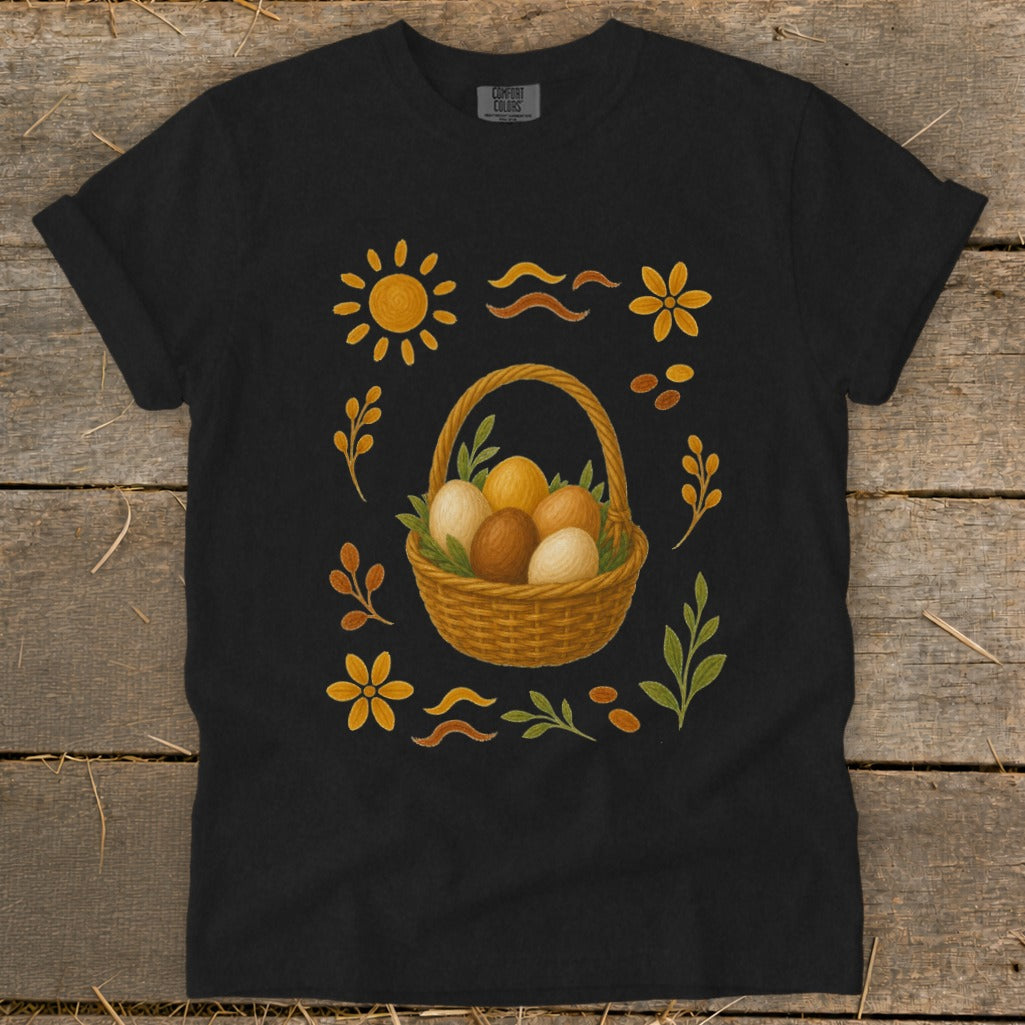 Black t-shirt with a woven basket of Easter eggs surrounded by sun, flowers, and leaves.