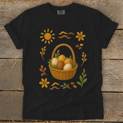 Black t-shirt with a woven basket of Easter eggs surrounded by sun, flowers, and leaves.