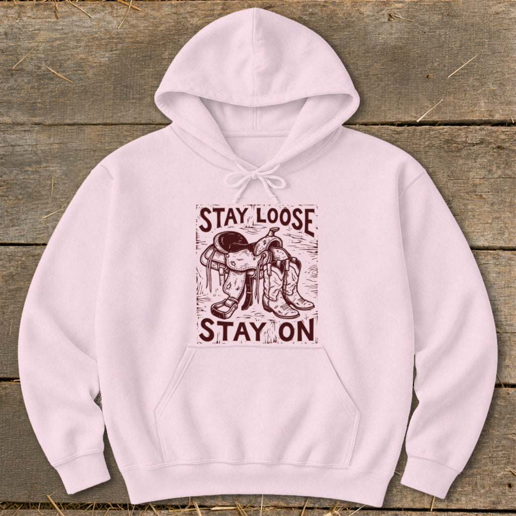 Pink hoodie with a saddle and cowboy boots graphic saying "STAY LOOSE STAY ON".