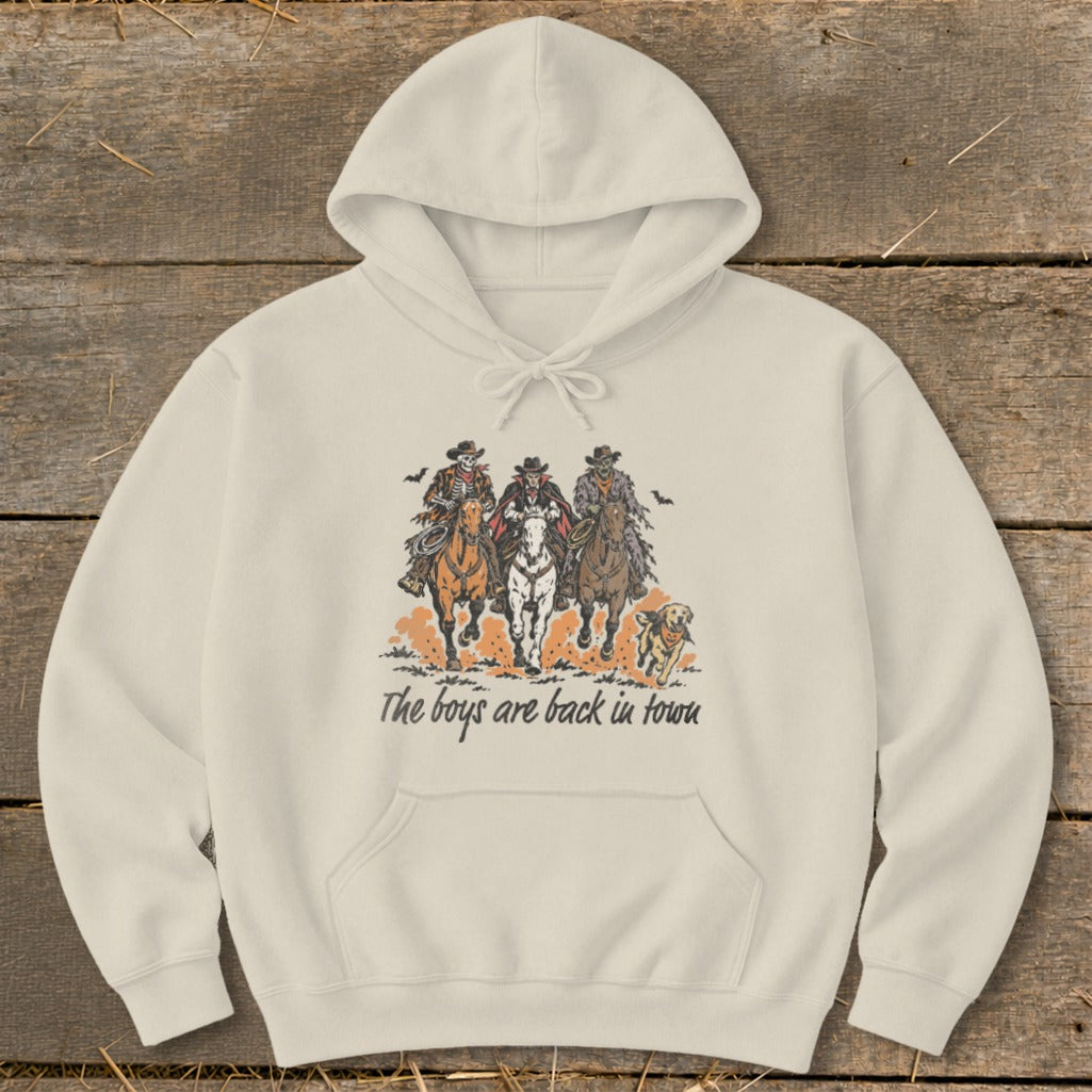 Skeleton, vampire, and zombie cowboys ride horses with a dog, text reads "The boys are back in town".