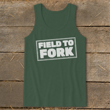 A dark green tank top featuring the white distressed text FIELD TO FORK centered on the chest, laid flat against a rustic wooden background.