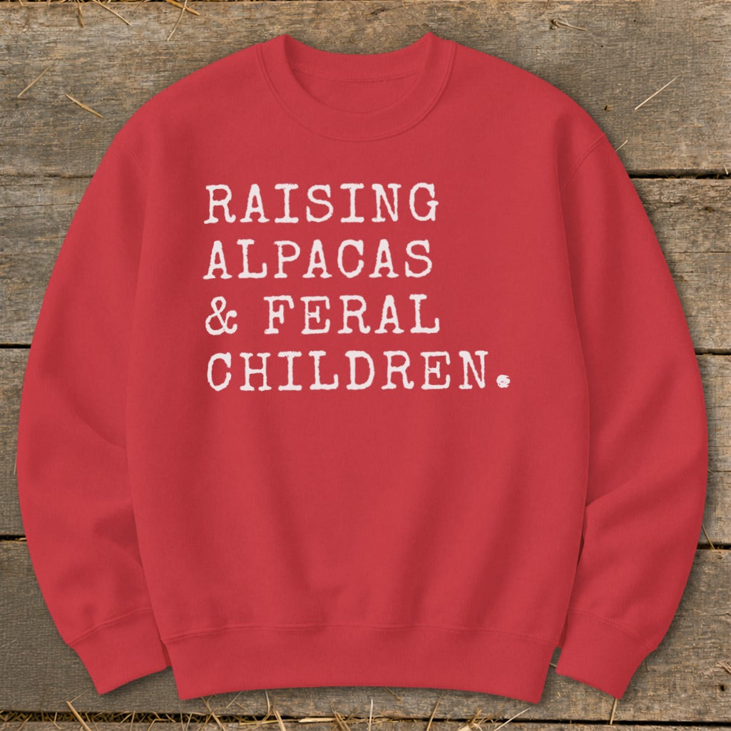 Red sweatshirt with white text: "RAISING ALPACAS & FERAL CHILDREN."