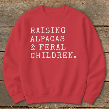 Red sweatshirt with white text: "RAISING ALPACAS & FERAL CHILDREN."