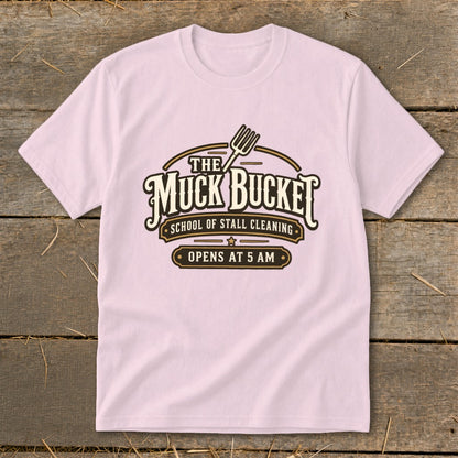 Pink t-shirt with "The Muck Bucket School of Stall Cleaning Opens at 5 AM" logo.