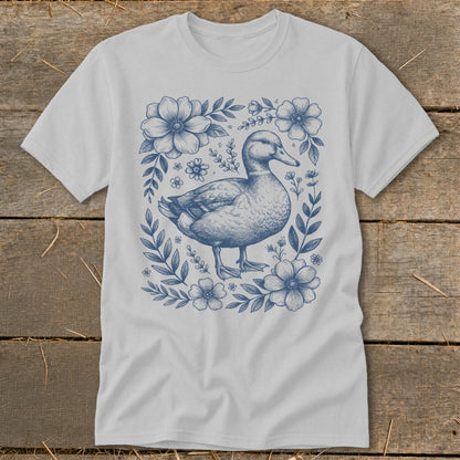 White t-shirt with a blue line drawing of a duck surrounded by flowers.