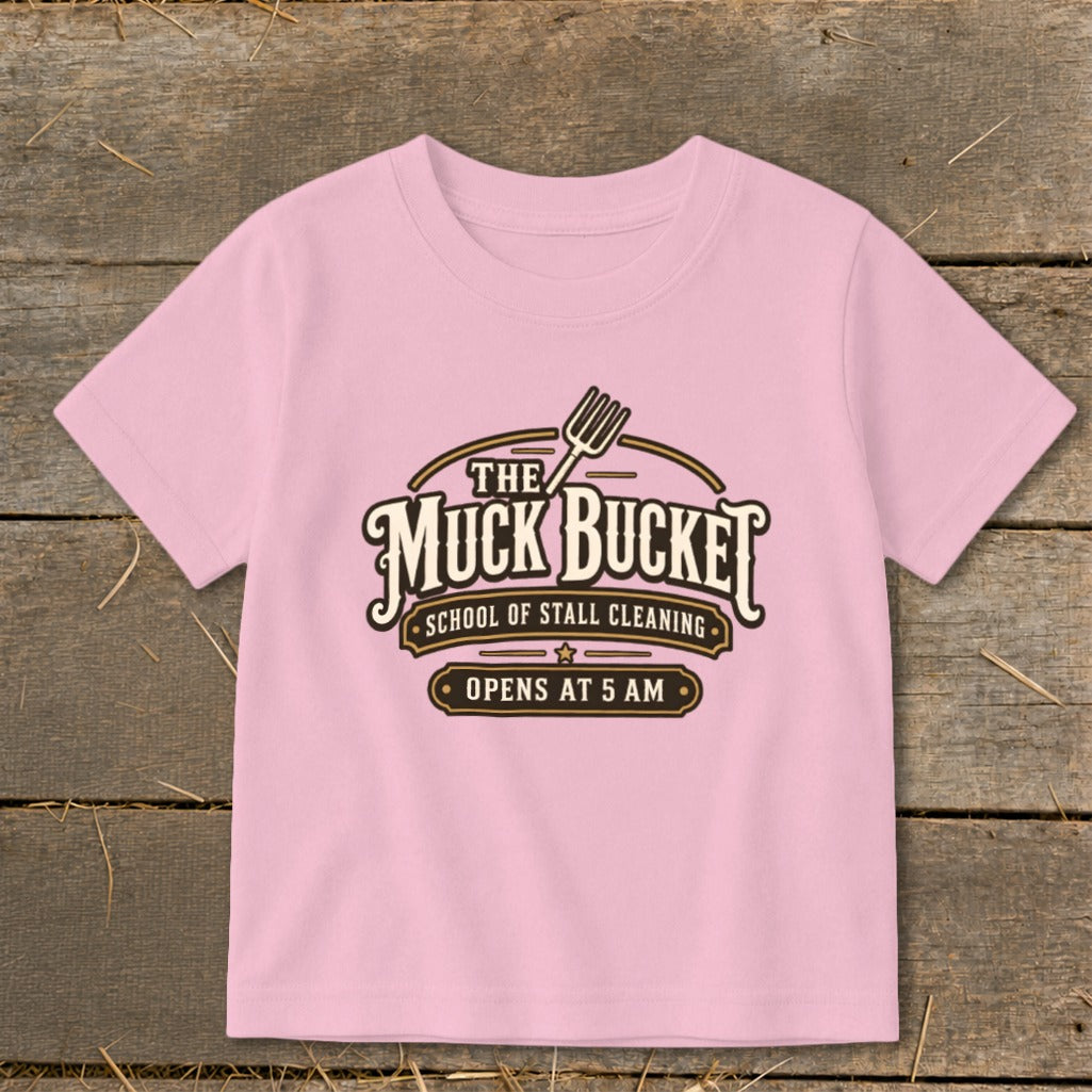 Pink t-shirt with "The Muck Bucket School of Stall Cleaning" graphic.