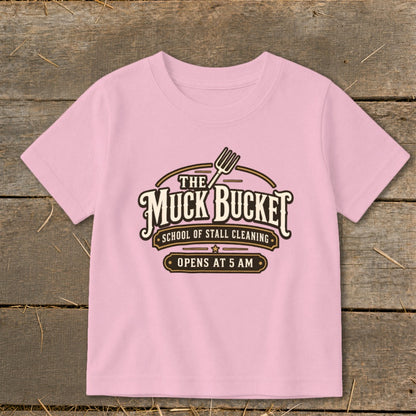 Pink t-shirt with "The Muck Bucket School of Stall Cleaning" graphic.