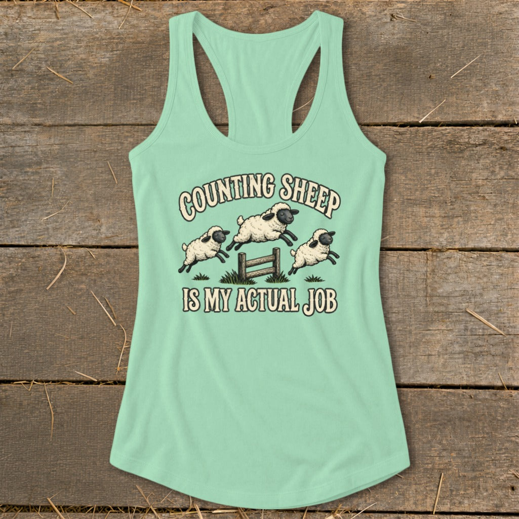 Mint green tank top with three sheep jumping over a fence, text reads "COUNTING SHEEP IS MY ACTUAL JOB".