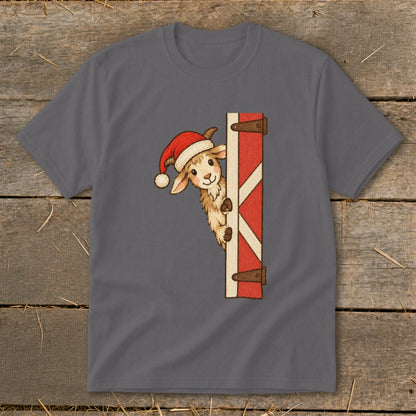 Christmas goat wearing a Santa hat peeking around a red barn door.