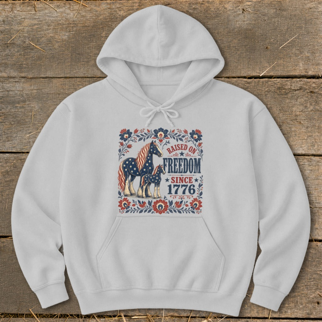 Light gray hoodie with a graphic of two horses and the text "Raised on Freedom Since 1776".