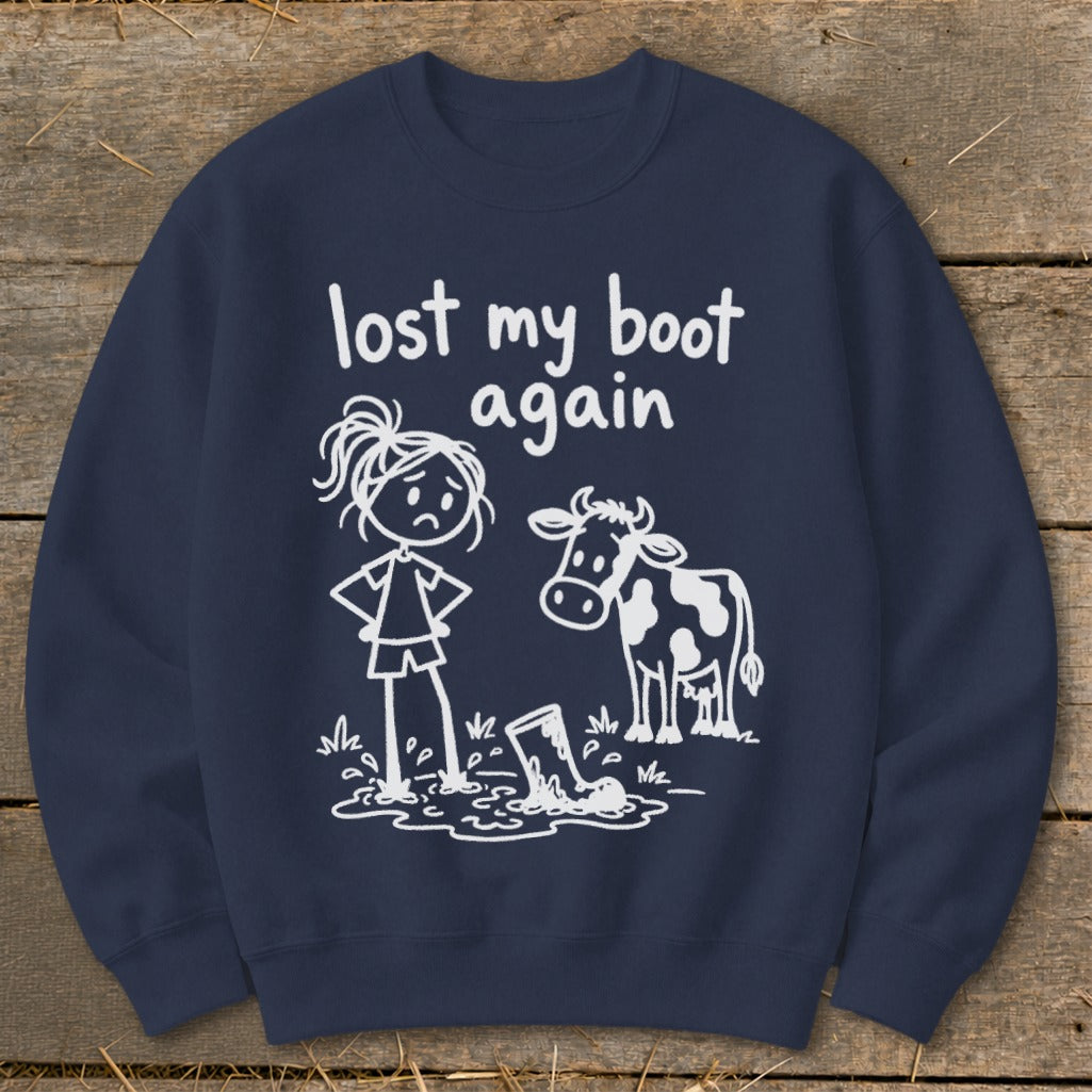 Dark blue crewneck sweatshirt featuring white graphic of a frustrated stick-figure woman, a cow, and text reading "lost my boot again."
