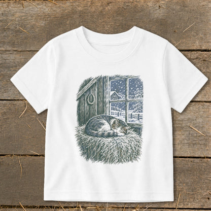 T-shirt with illustration of a sleeping cat on hay next to a snowy window.