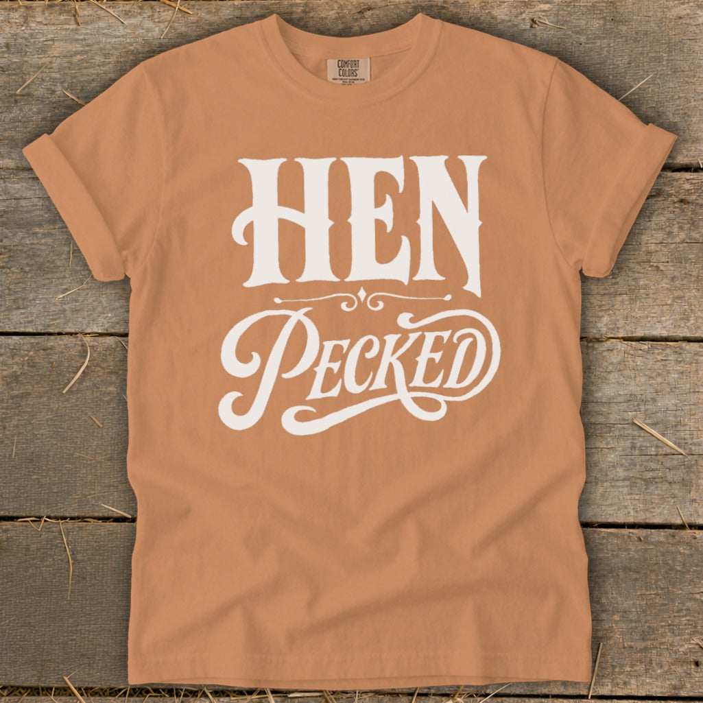 Orange t-shirt with white text "HEN Pecked" in decorative fonts.