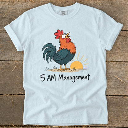 White t-shirt features a cartoon rooster greeting the sunrise with "5 AM Management" text.