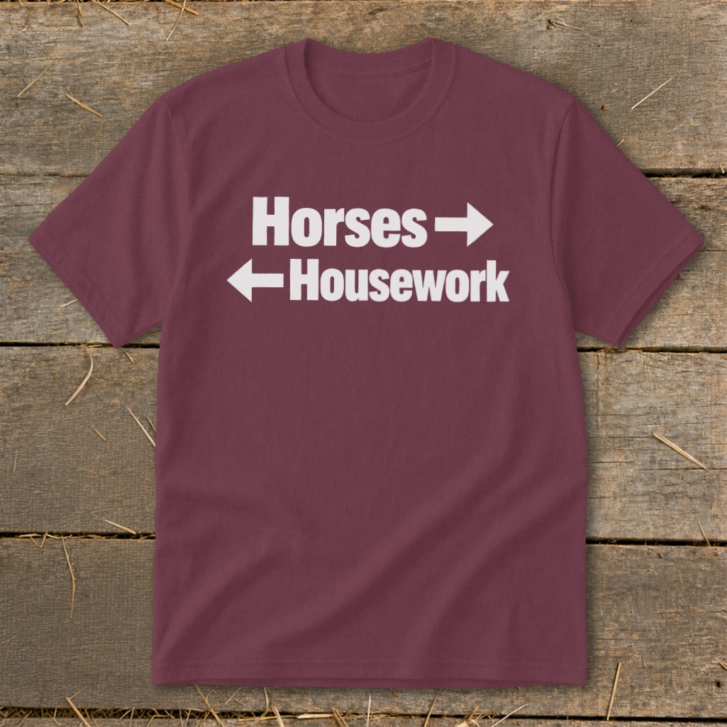 A maroon t-shirt with white text reading "Horses" pointing right and "Housework" pointing left.