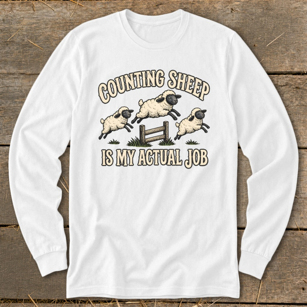 White long-sleeved shirt with graphic "Counting Sheep Is My Actual Job".