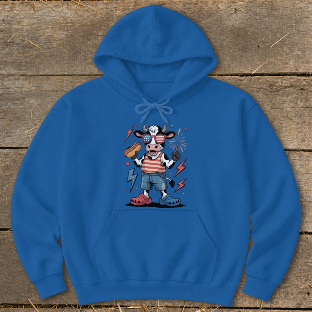Cartoon cow wearing sunglasses and American flag shirt holding a hot dog.