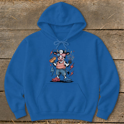 Cartoon cow wearing sunglasses and American flag shirt holding a hot dog.