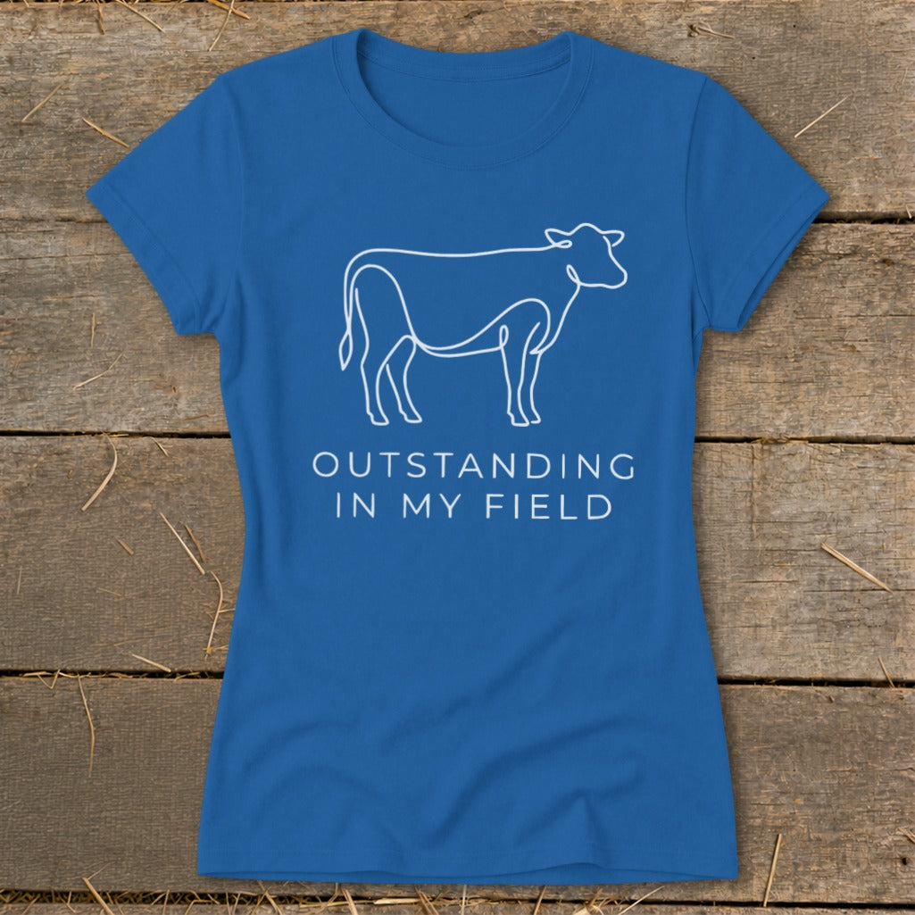 Blue t-shirt with white line drawing of a cow and text "OUTSTANDING IN MY FIELD".