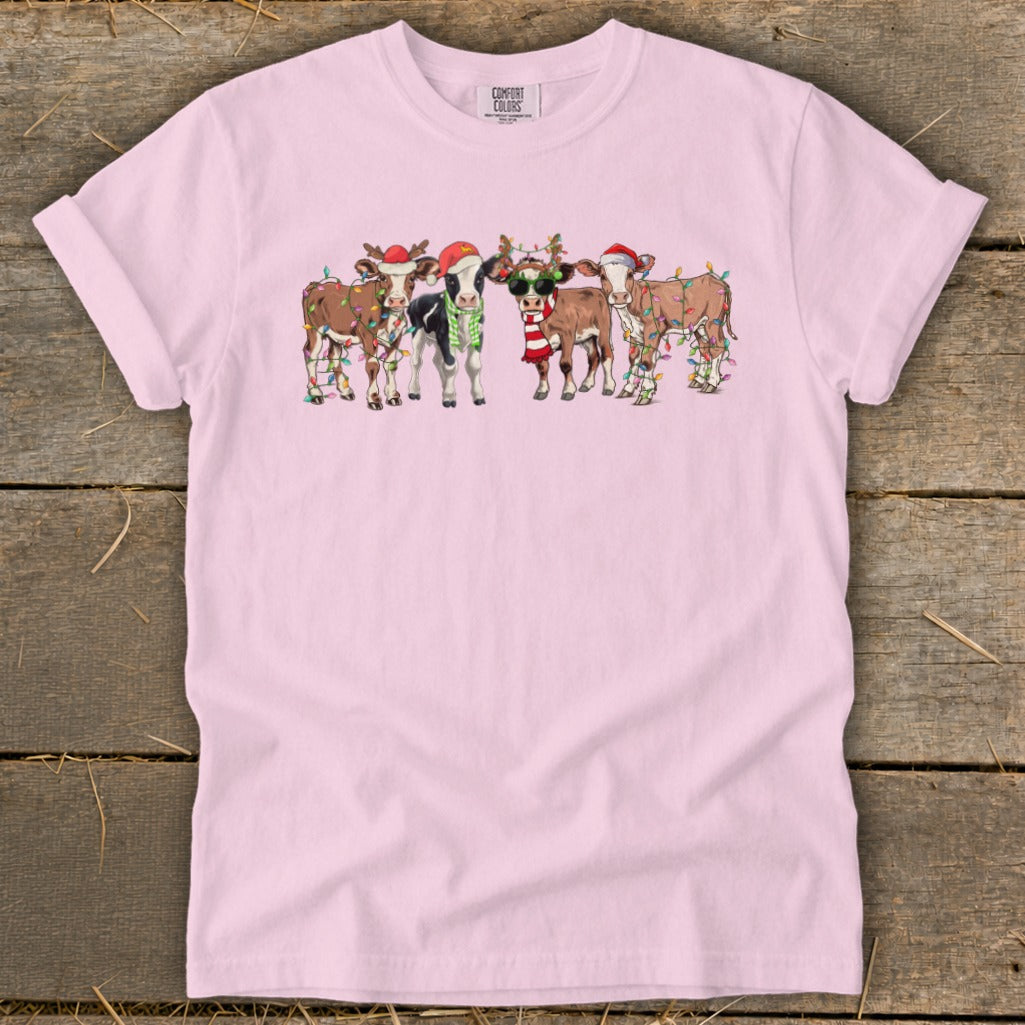 Pink t-shirt with a graphic of cows wearing Santa hats and Christmas lights.