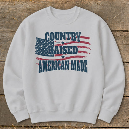 White sweatshirt with "COUNTRY RAISED AMERICAN MADE" text and distressed American flag graphic.