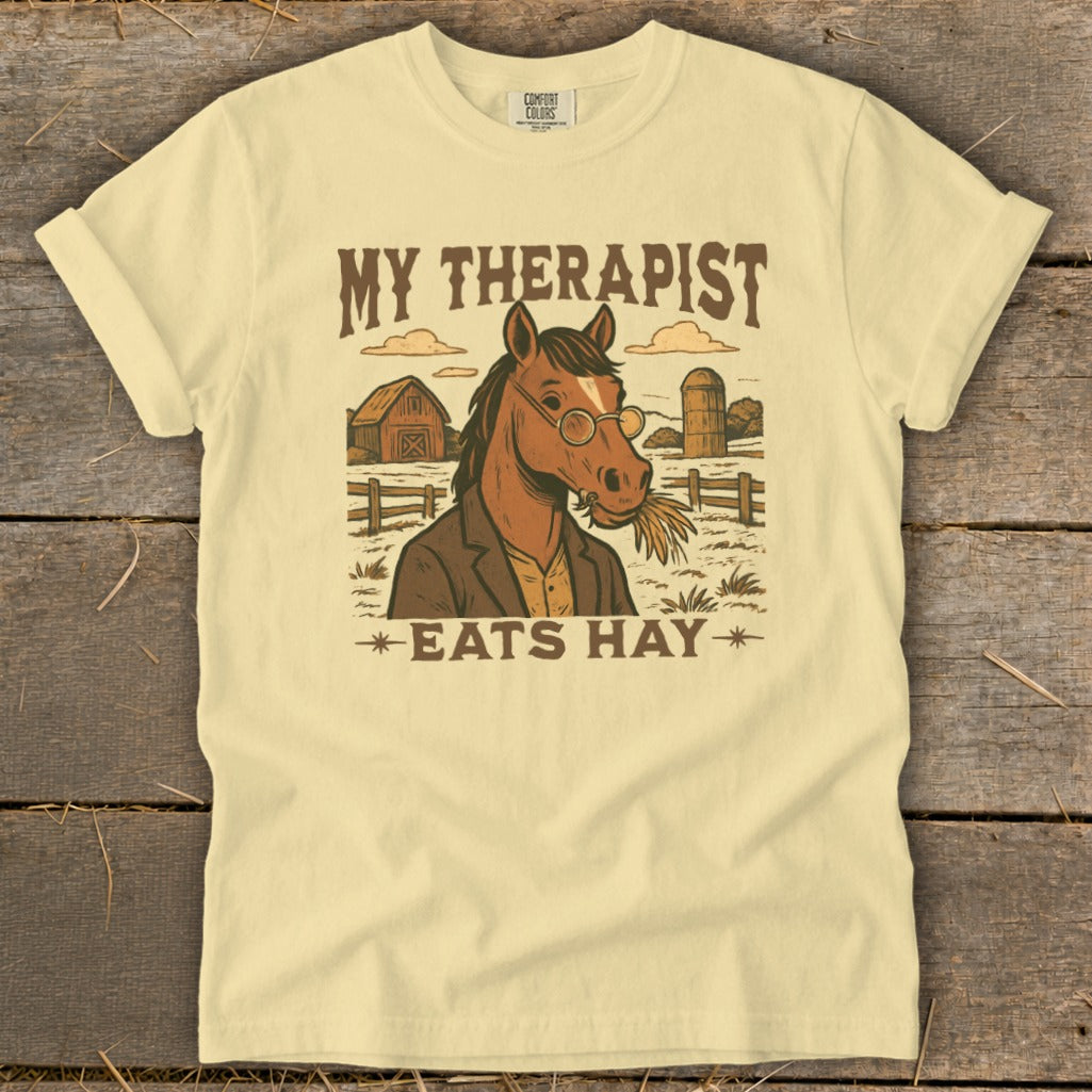T-shirt graphic with a horse wearing glasses and a jacket, with text "My therapist eats hay".