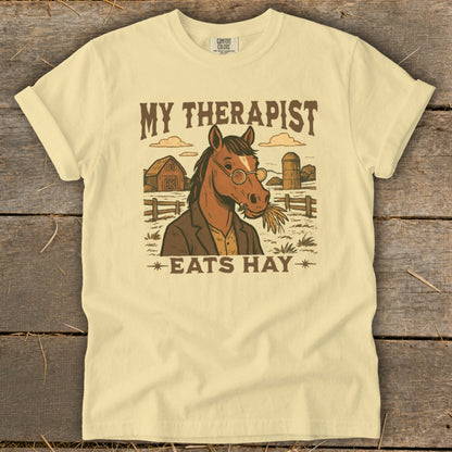 T-shirt graphic with a horse wearing glasses and a jacket, with text "My therapist eats hay".