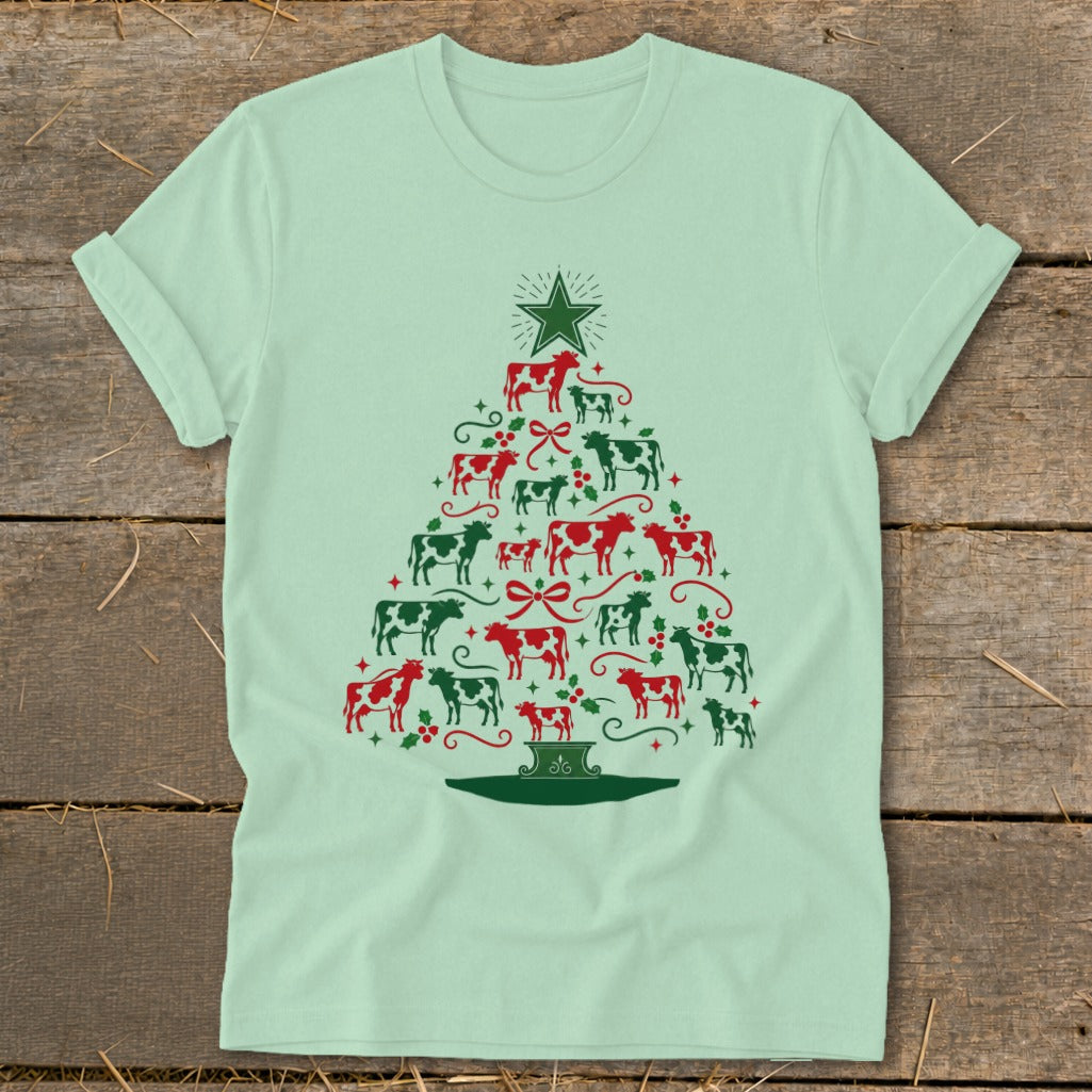 Light green t-shirt with a Christmas tree made of red and green cows and holly.