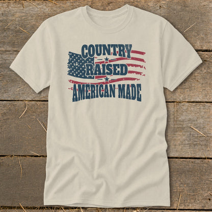 Cream t-shirt with distressed American flag graphic and text "COUNTRY RAISED AMERICAN MADE".