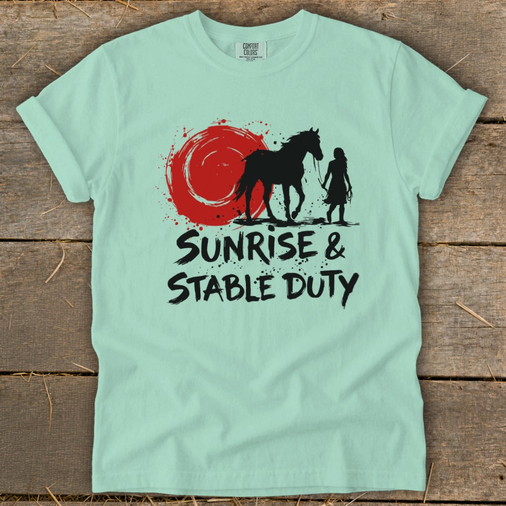 Mint green t-shirt with black graphic of horse and rider with red sun and text "Sunrise & Stable Duty".