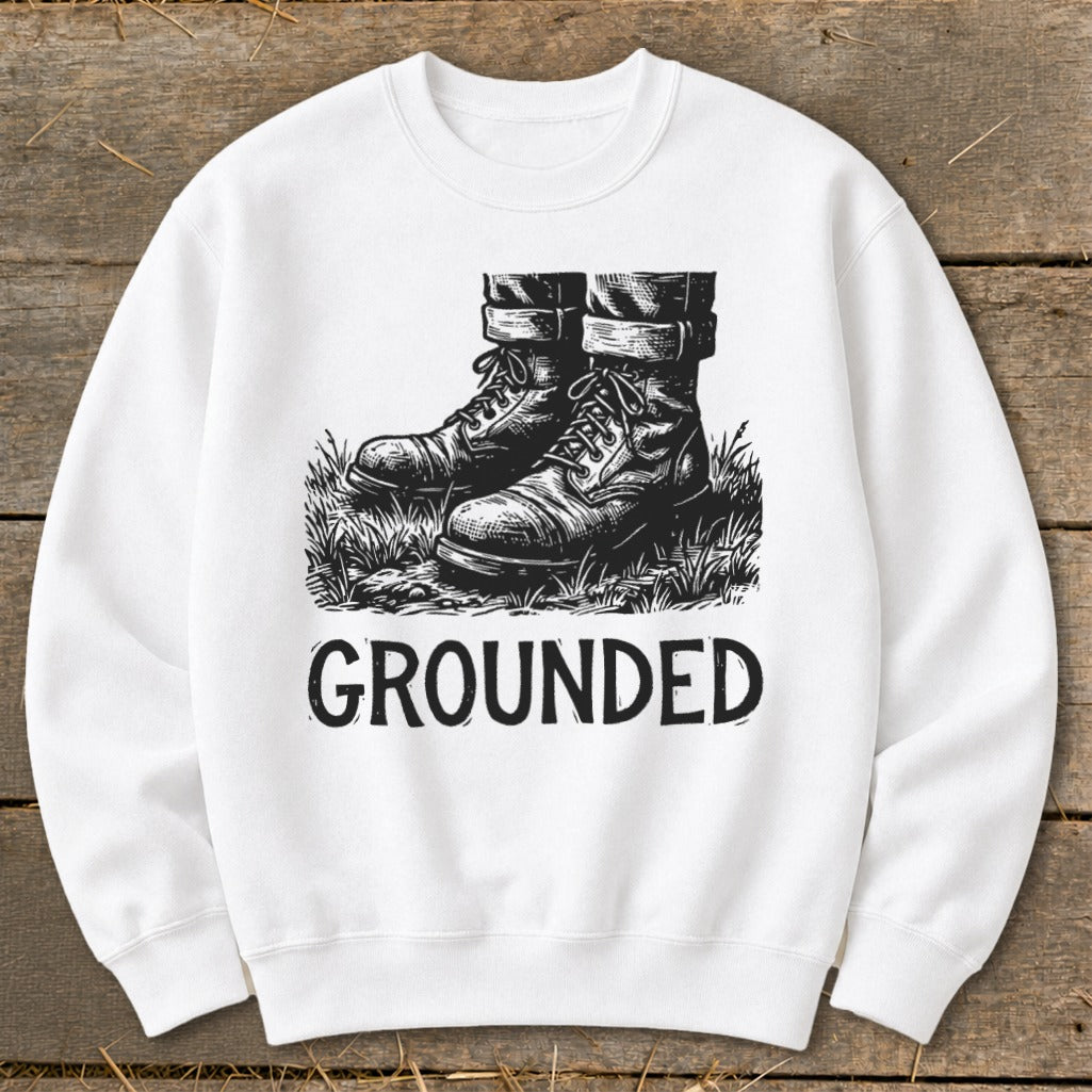 White sweatshirt with graphic of boots in grass and text "GROUNDED".