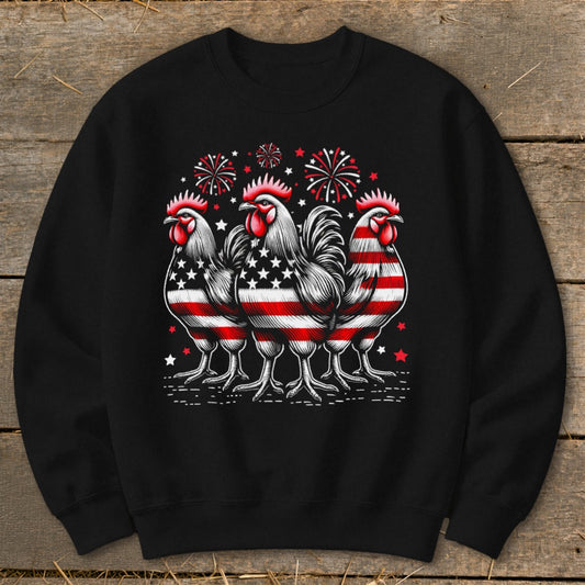 Three roosters with American flag patterns stand in front of fireworks.