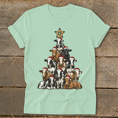 Light green t-shirt with a Christmas tree made of cows wearing Santa hats.