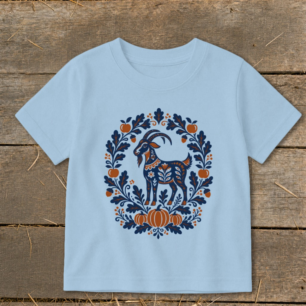 Light blue children's t-shirt featuring a folk-art goat illustration surrounded by an autumn wreath.