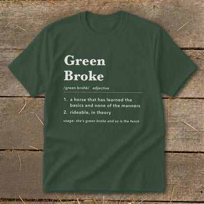 A dark green crewneck t-shirt featuring dictionary-style text that defines green broke on a rustic wooden background.