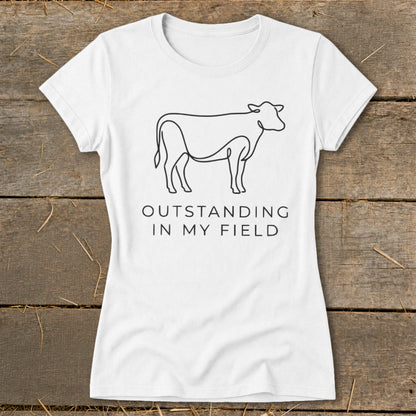 White t-shirt with line art of a cow and text "OUTSTANDING IN MY FIELD".