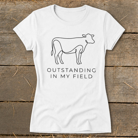 White t-shirt with line art of a cow and text "OUTSTANDING IN MY FIELD".