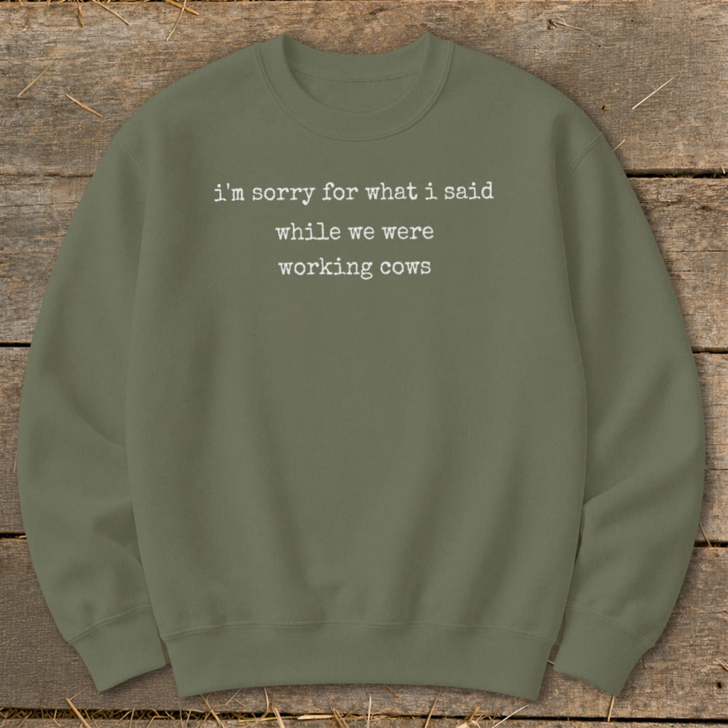 Olive green sweatshirt with white text "i'm sorry for what i said while we were working cows."