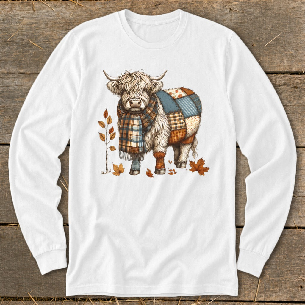 White long sleeve shirt with a Highland cow wearing a scarf and patchwork blanket.