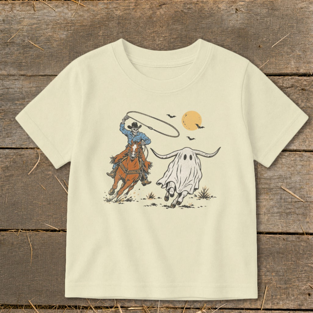 Skeleton cowboy on horseback lassoing a longhorn ghost with bats and a moon.