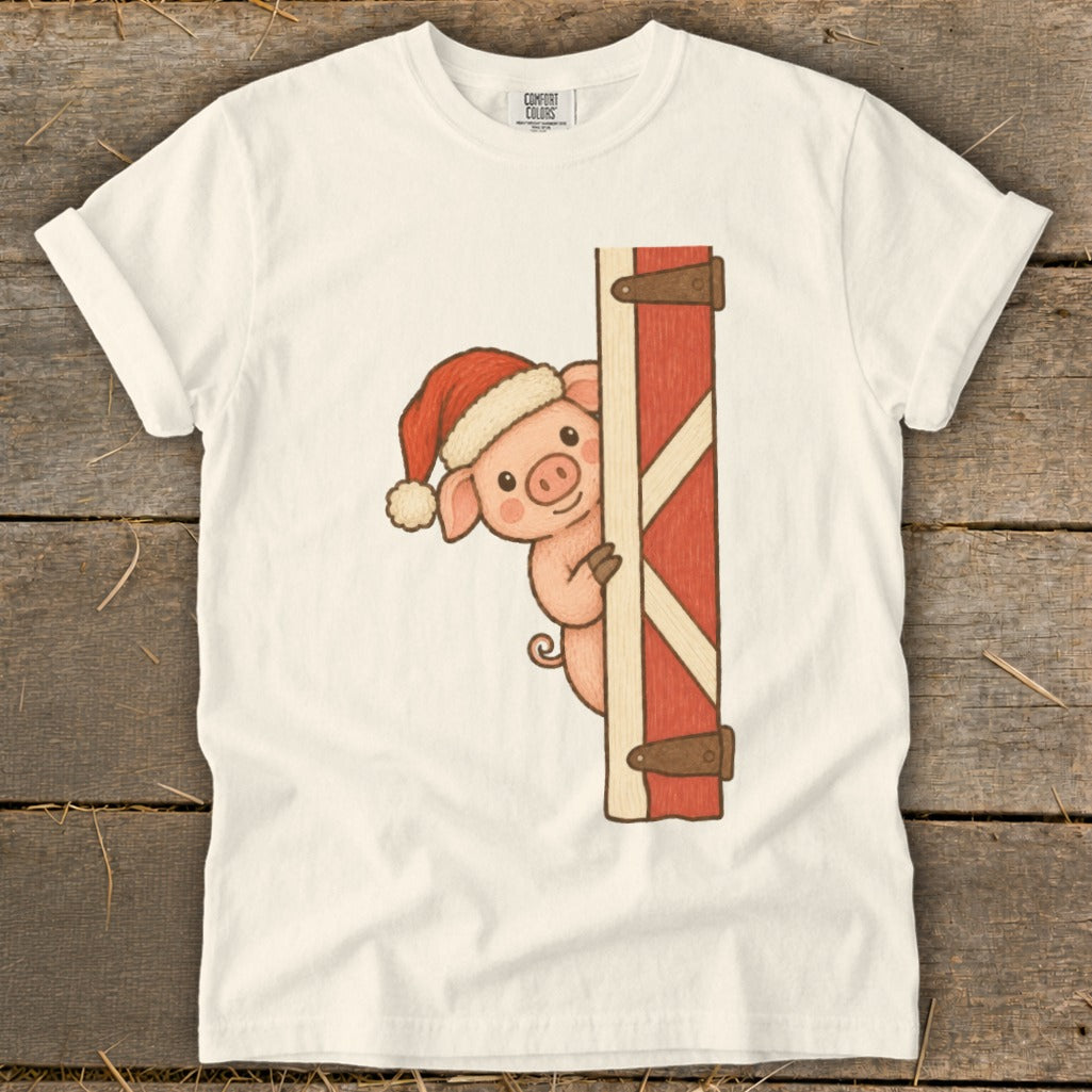Pig wearing Santa hat peeks from behind a red barn door.